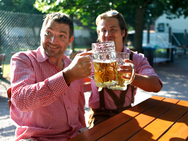 Two guys raising steins of beer at Oktoberfest