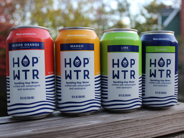 Four cans of various flavors of Hop Wtr, including Blood Orange, Classic, Lime and Mango
