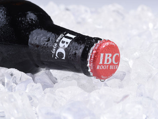 A cold bottle of IBC Root Beer laid over a bed of ice