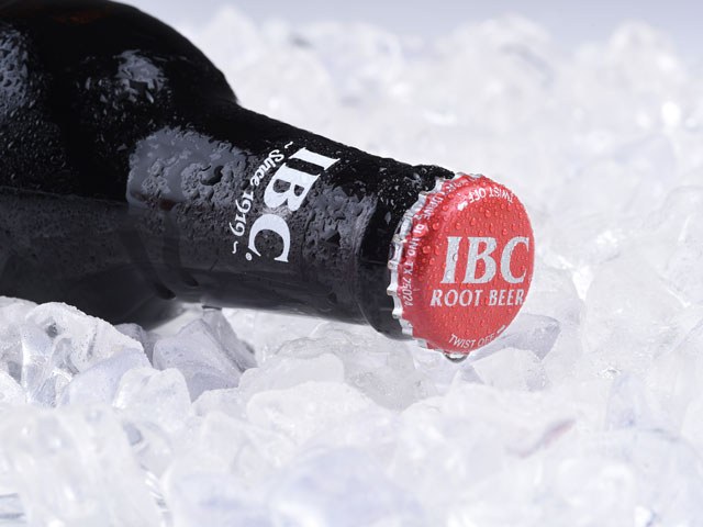 A cold bottle of IBC Root Beer laid over a bed of ice