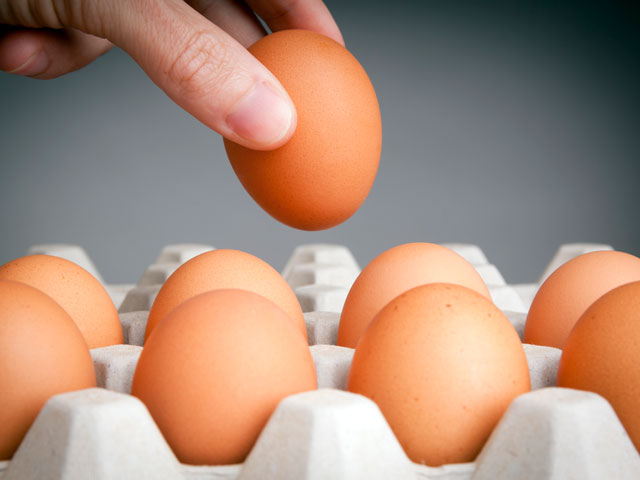 A person choosing an egg from a carton to put in their beer glass